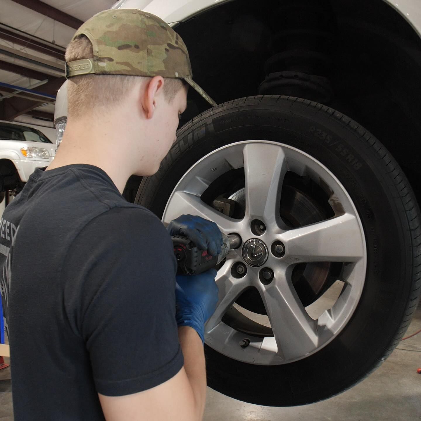 A man wearing a hat is working on a car wheel