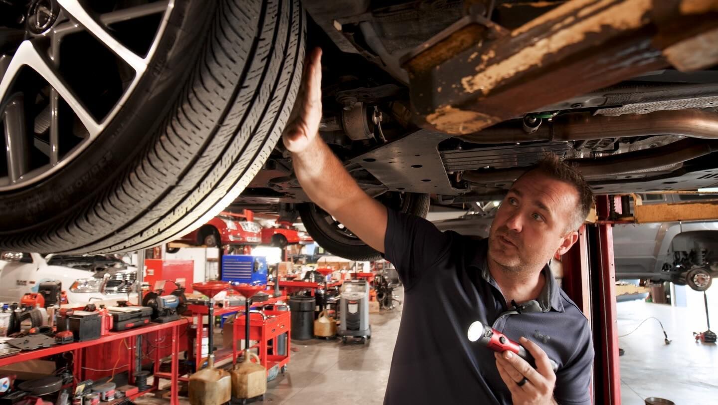 A man is working under a car in a garage.