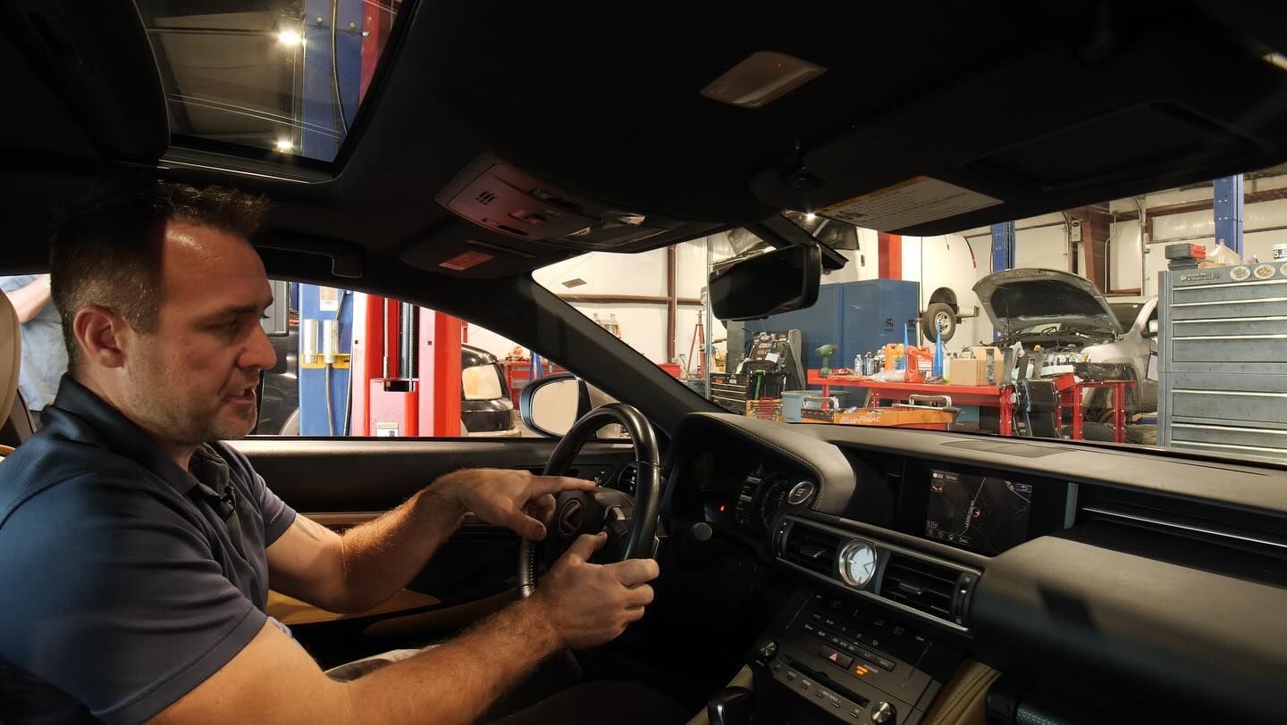 A man is sitting in the driver 's seat of a car in a garage.