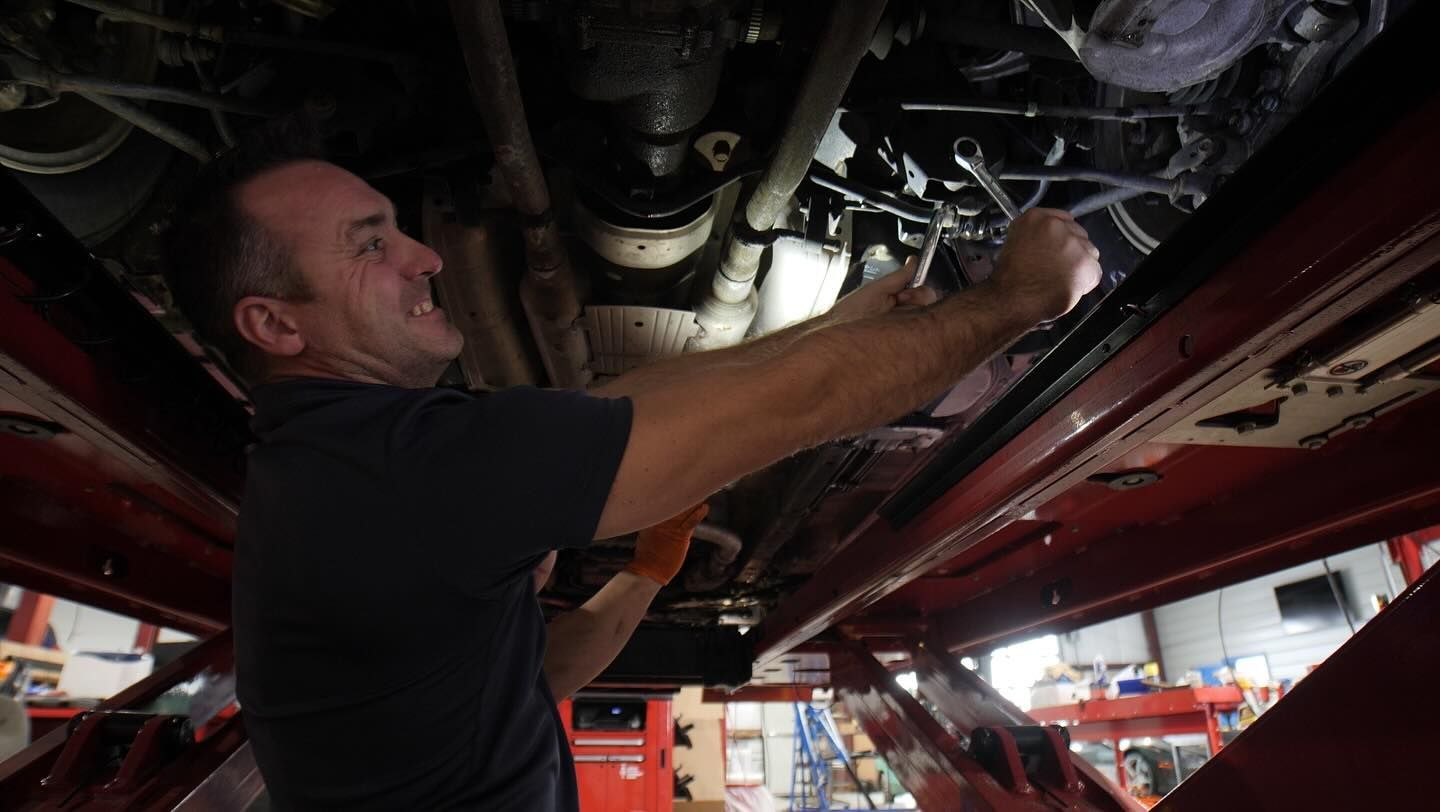 A man is working underneath a car in a garage.