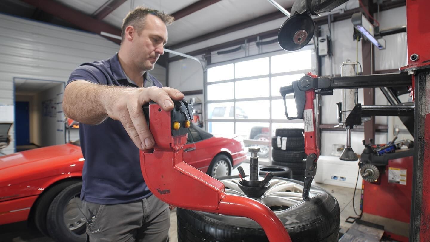 A man is working on a tire in a garage.