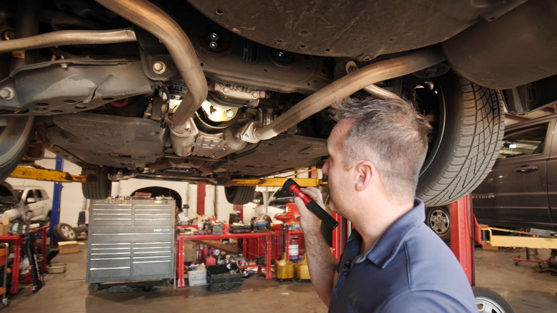 A man is working under a car in a garage.