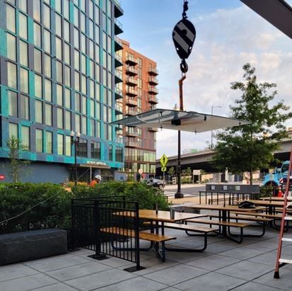 A crane is lifting a roof over a picnic area