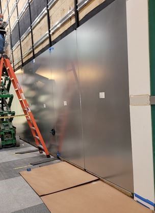 A man is standing on a ladder next to a large wall