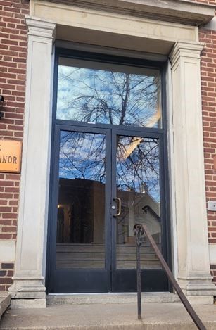 A brick building with a glass door and stairs leading up to it