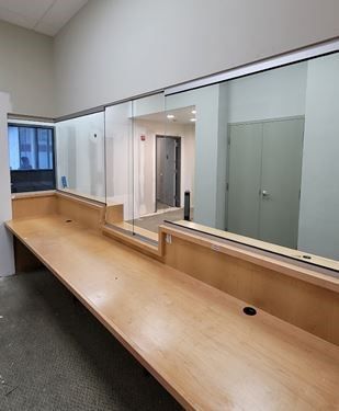 A long wooden desk situated in a room featuring a expansive glass window