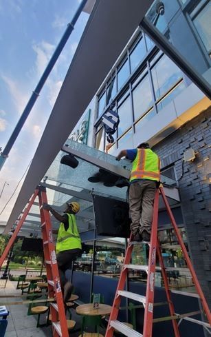 A couple of men standing on ladders working on a building