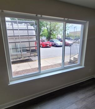 An empty room with a large window looking out to a parking lot