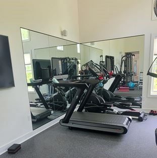 A gym with a treadmill and two expansive mirrored walls