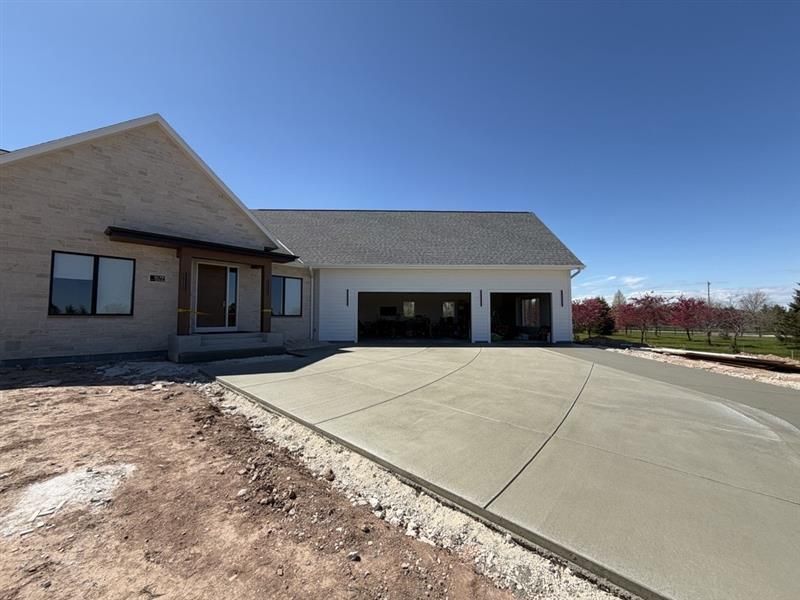 Single-story house with a large concrete driveway and attached garage under a clear blue sky