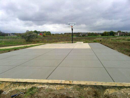 A basketball hoop is sitting on top of a concrete court.