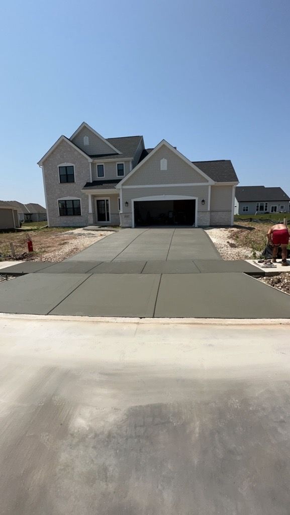 A group of people are working on a driveway in front of a house