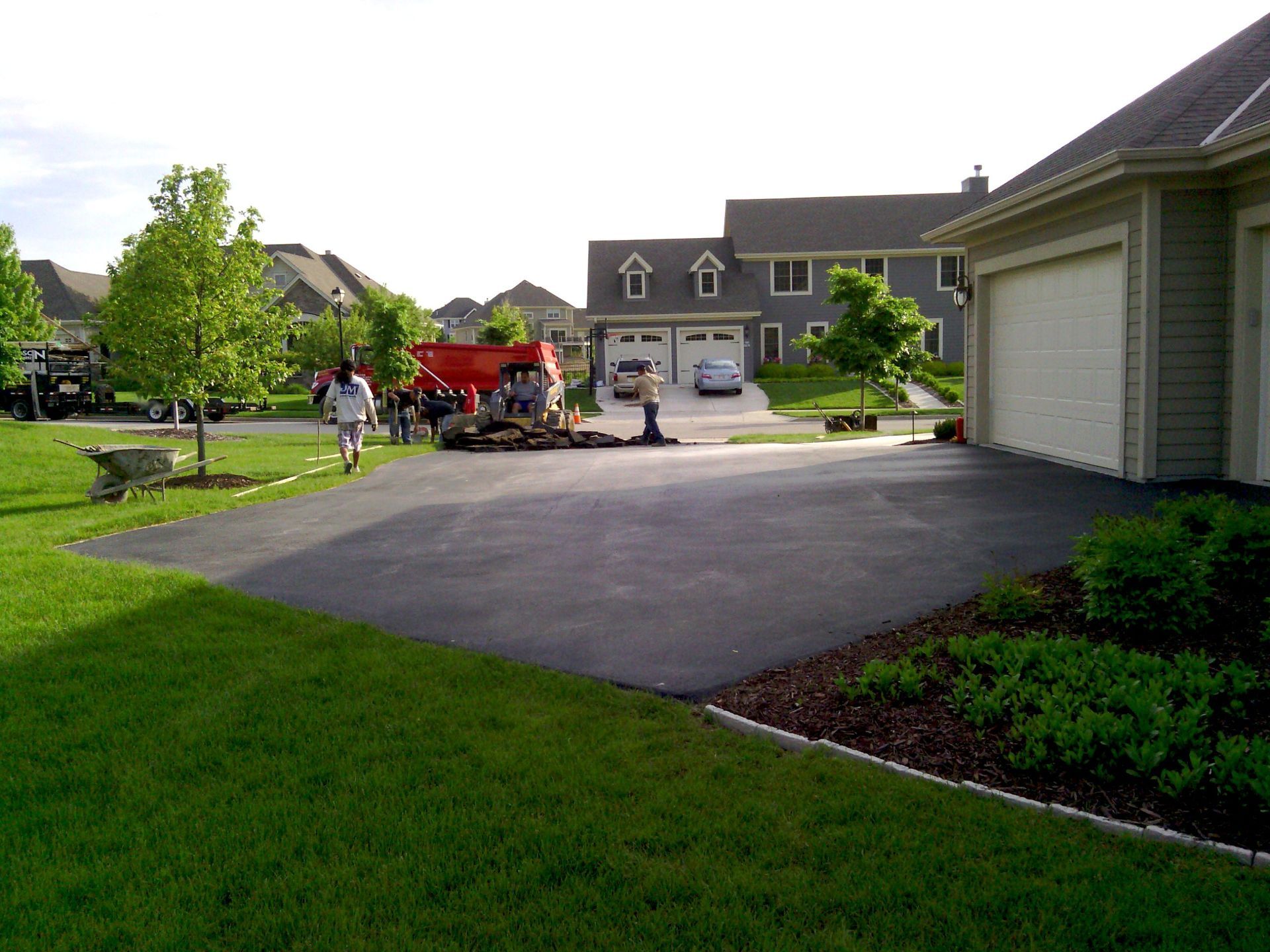 A group of people are working on a driveway in front of a house