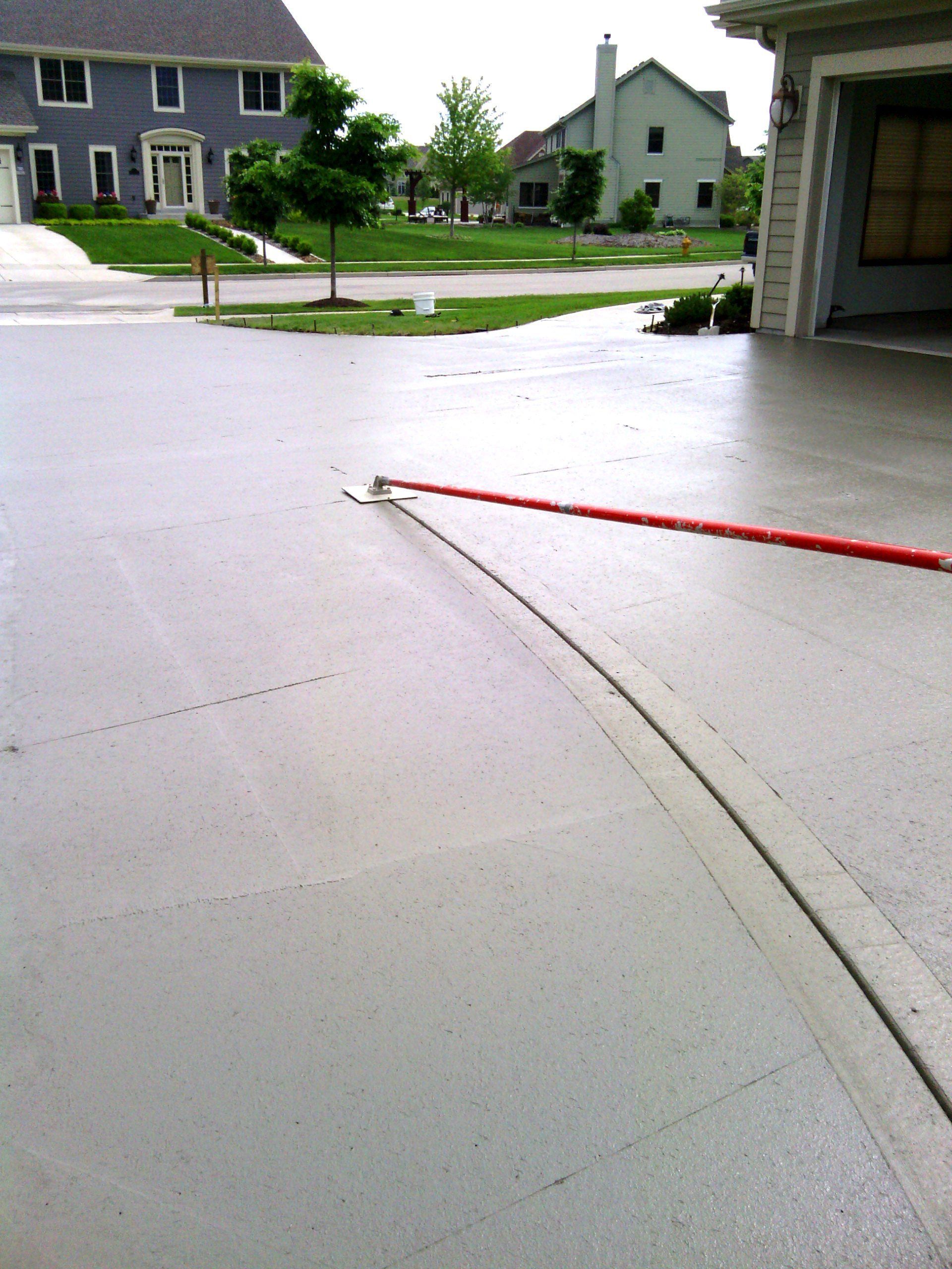 A concrete driveway with a red hose attached to it