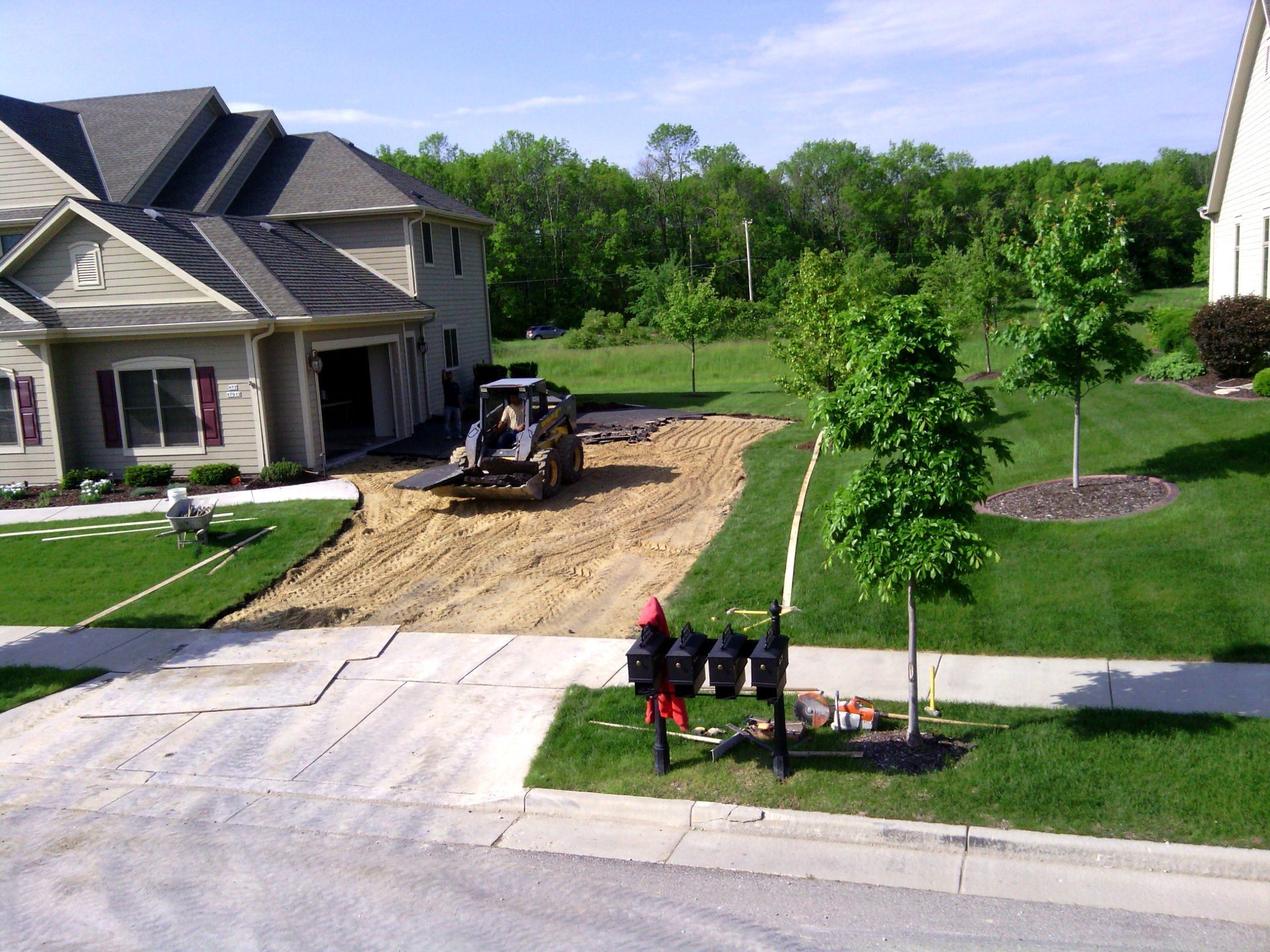 A tractor is moving dirt in front of a house