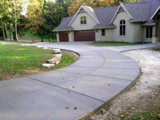 A curved concrete driveway leads to a large house