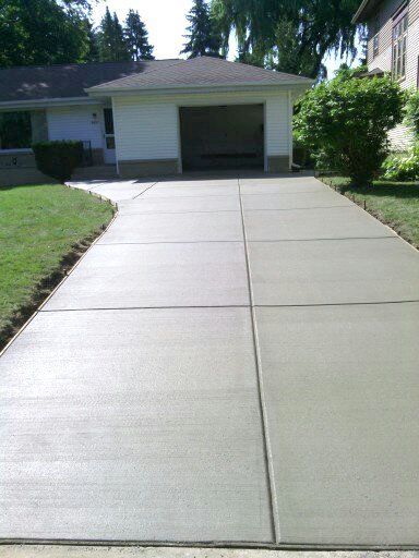 A concrete driveway leading to a house with a garage