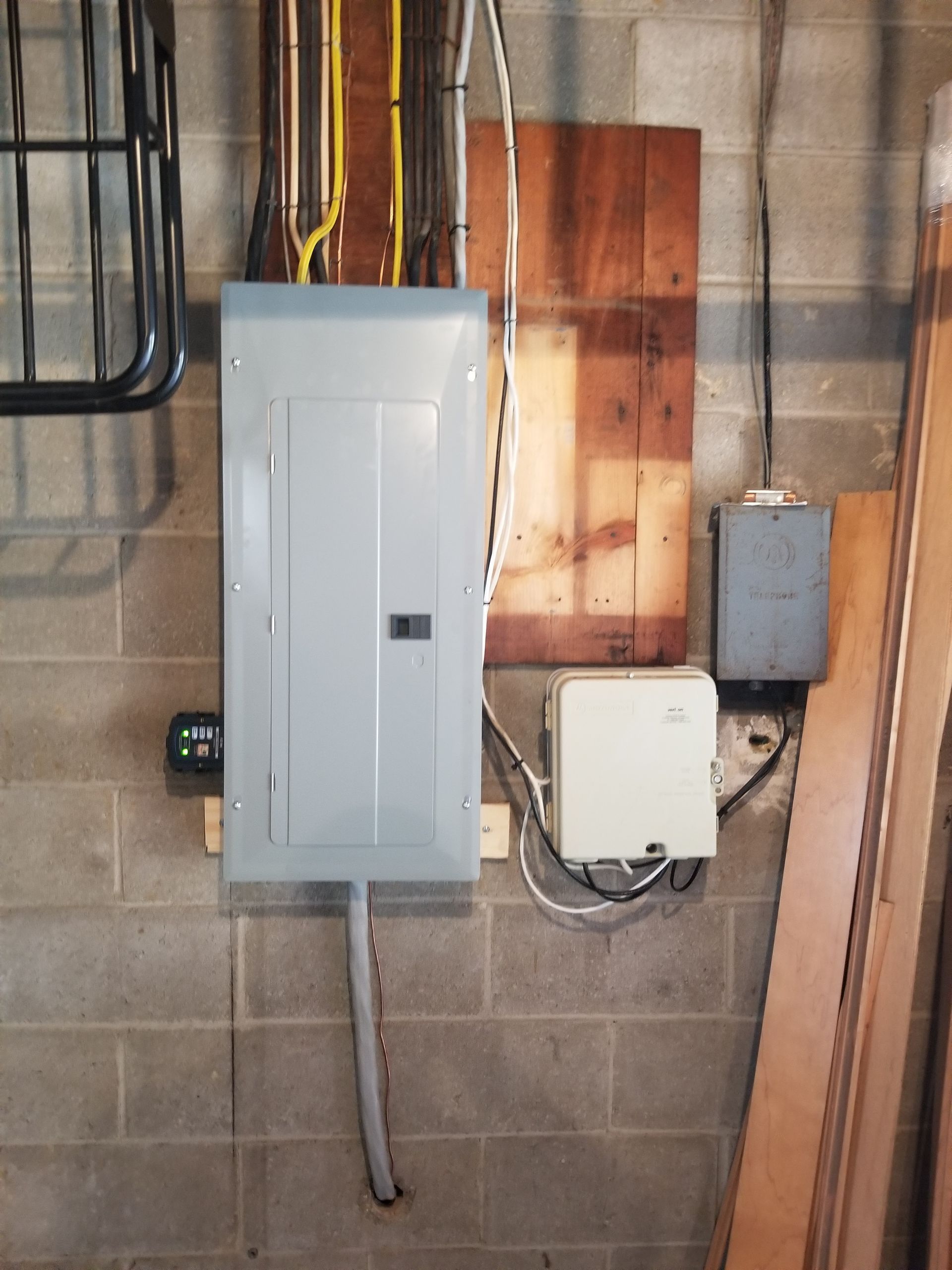 Electrical panel and junction boxes mounted on a concrete wall in a utility area.