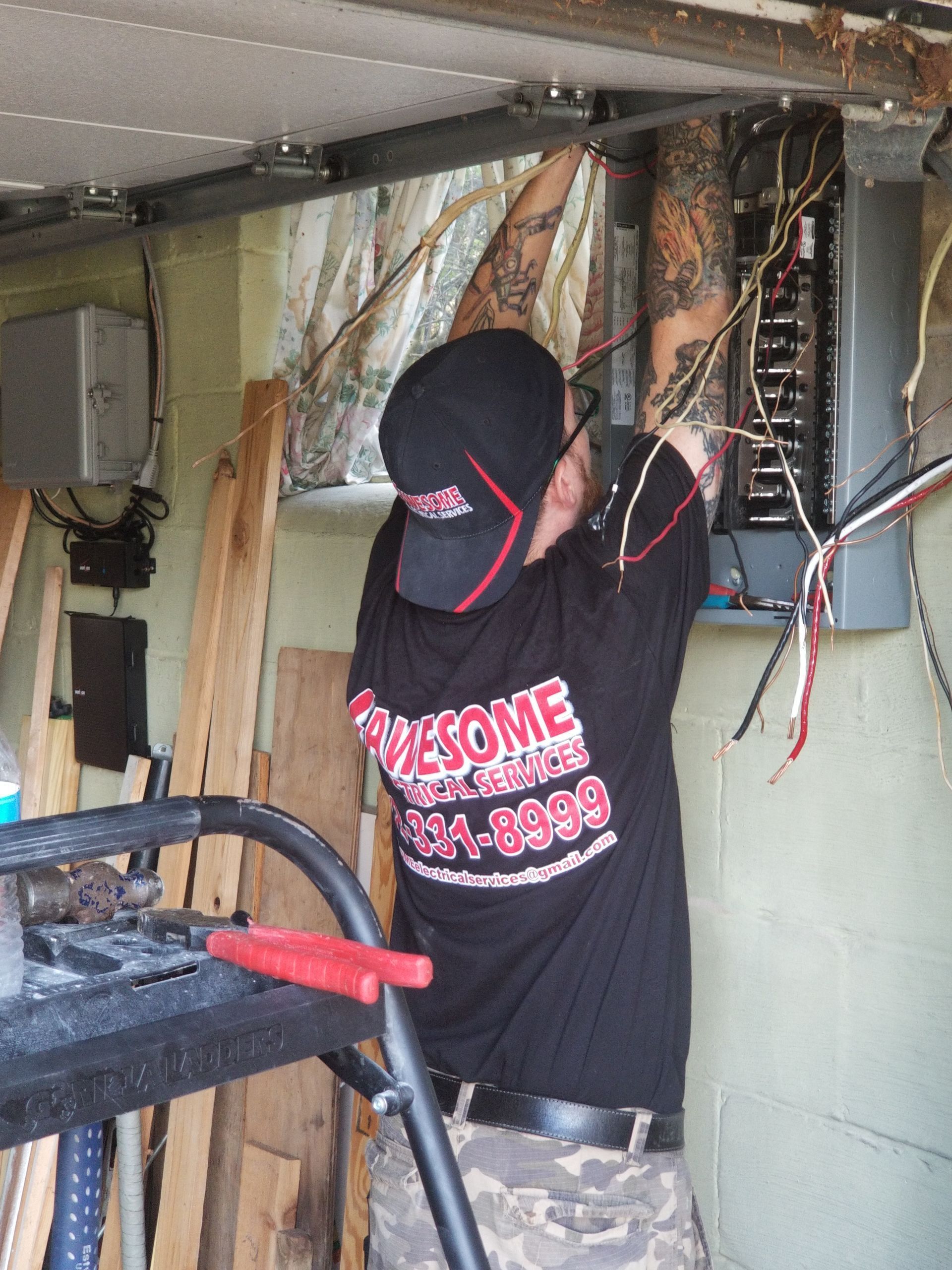 Person in black hoodie working on exposed wires in a damaged room