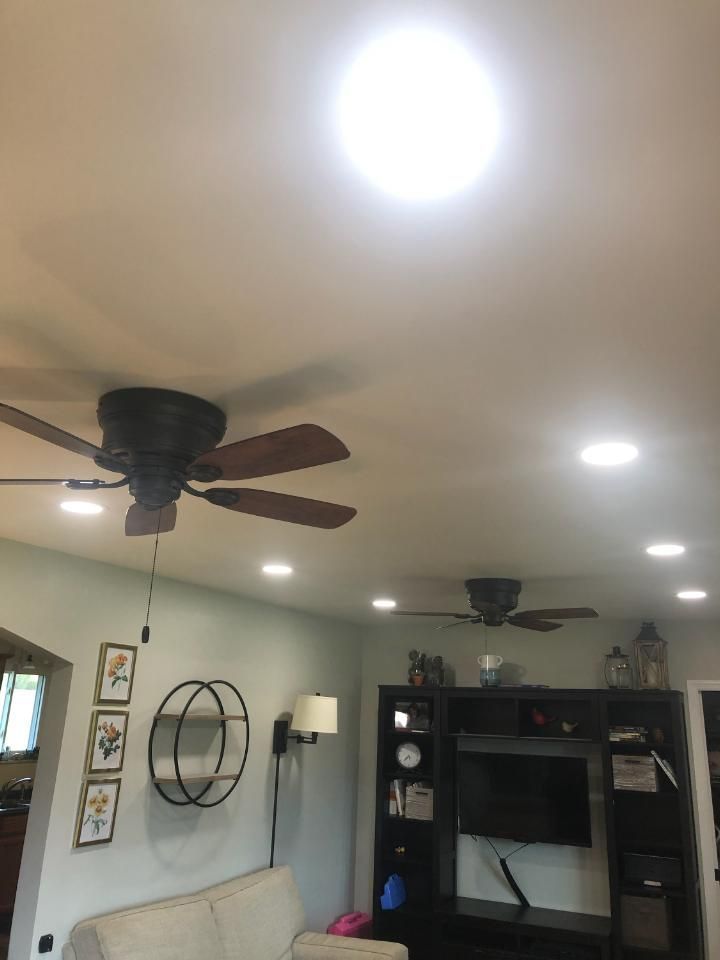 Living room with ceiling fans, recessed lights, wall decor, and a TV stand