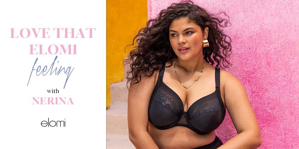 A woman in a black bra is sitting in front of a pink wall.