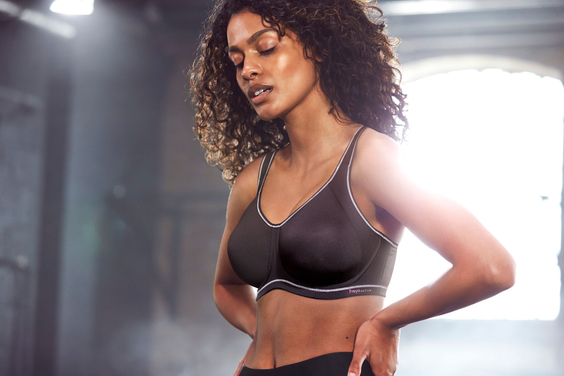 A woman is wearing a black sports bra and black pants.