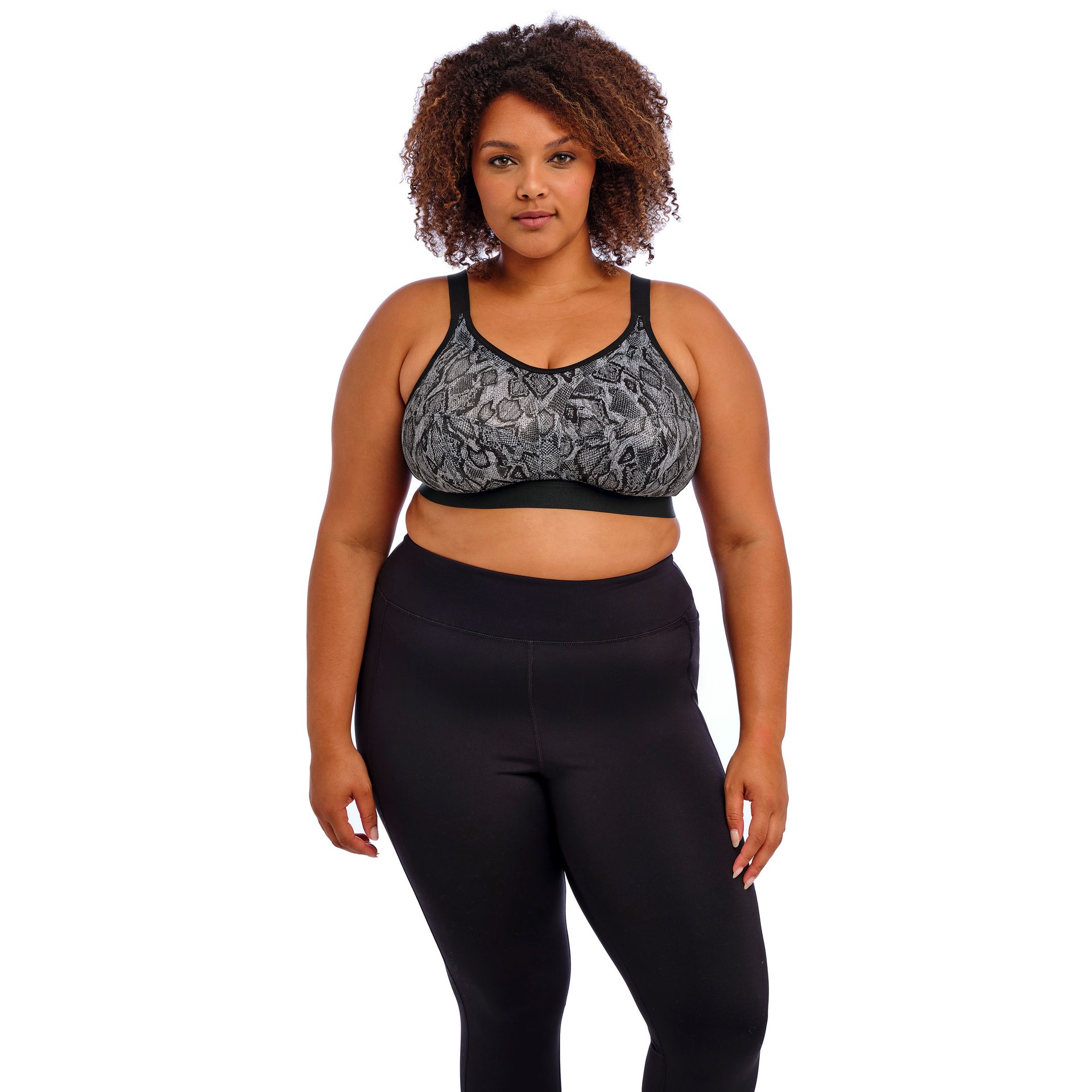 A plus size woman is wearing a sports bra and black leggings.