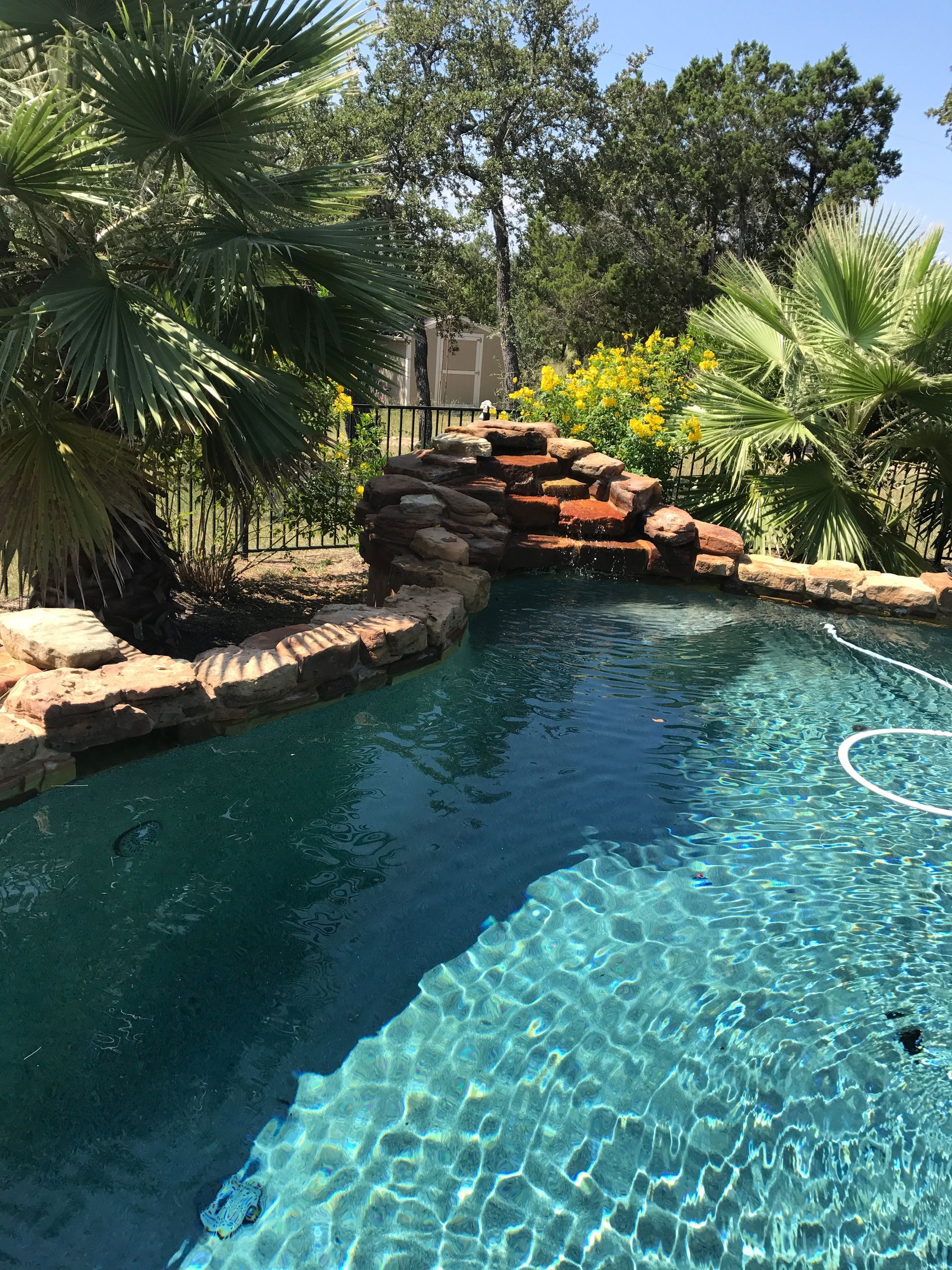 A large swimming pool with a waterfall in the backyard