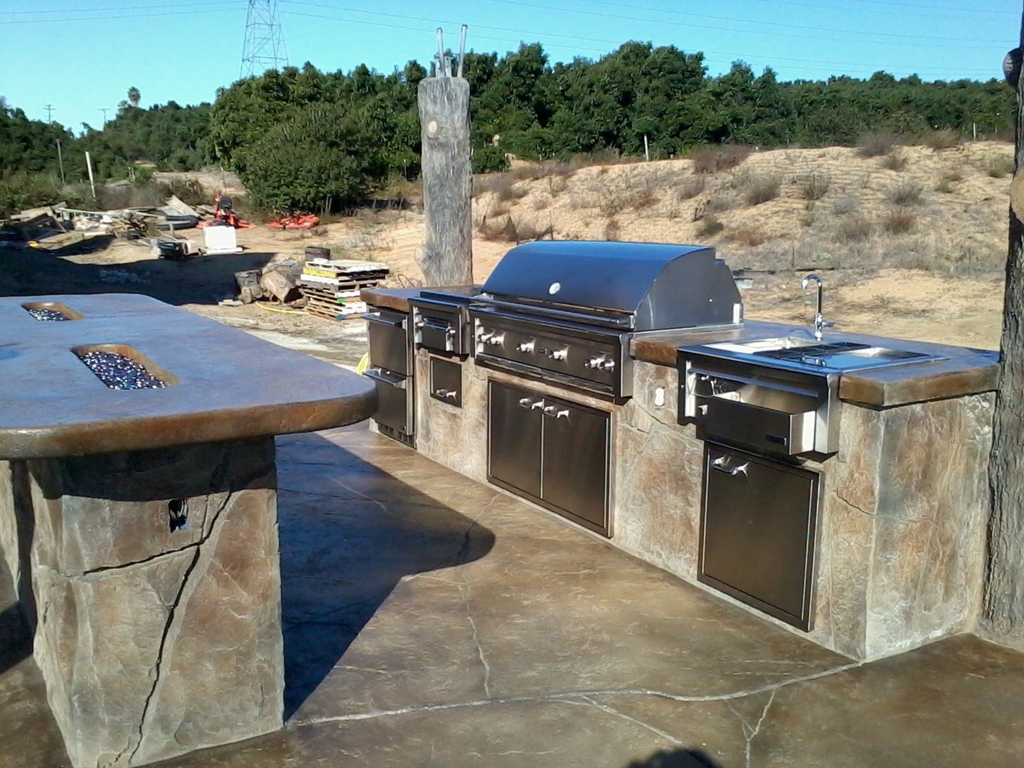 A large outdoor kitchen with a grill and sink