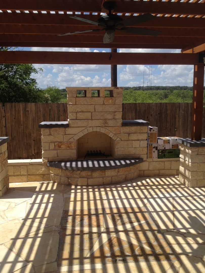 A brick fireplace under a pergola with a ceiling fan