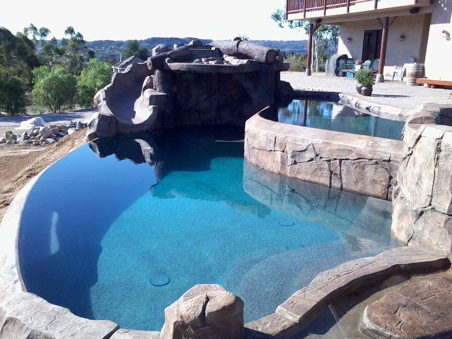 A large swimming pool with a slide and a house in the background