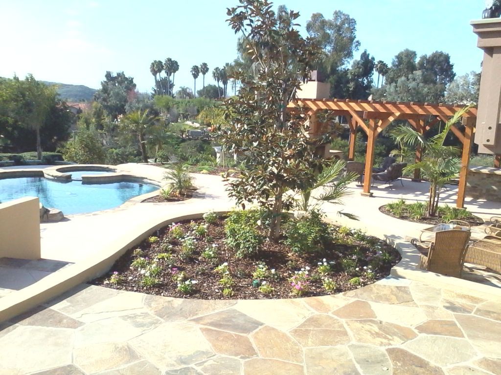 A patio with a pergola and a pool in the background
