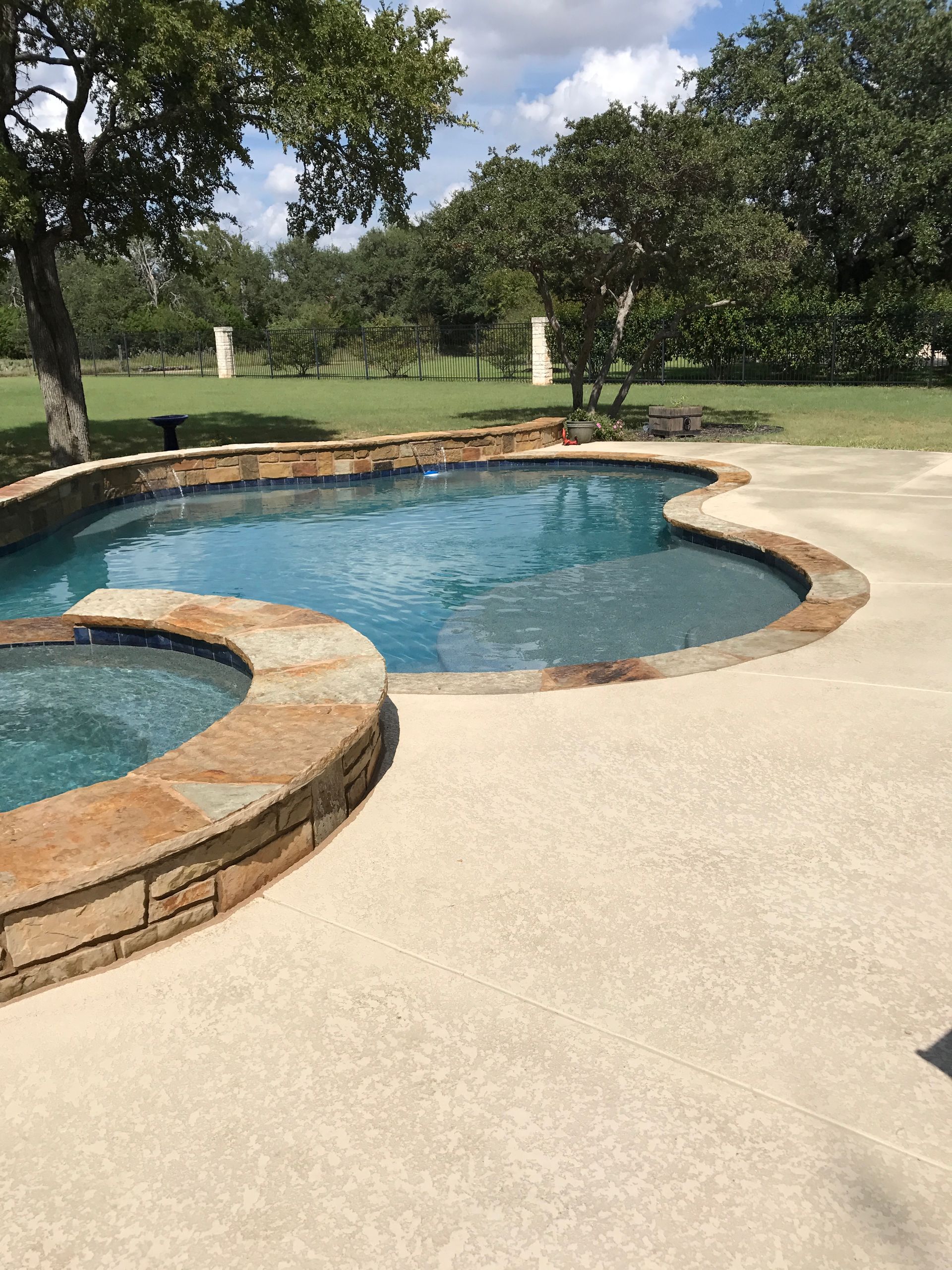 A large swimming pool with a hot tub in the middle of it