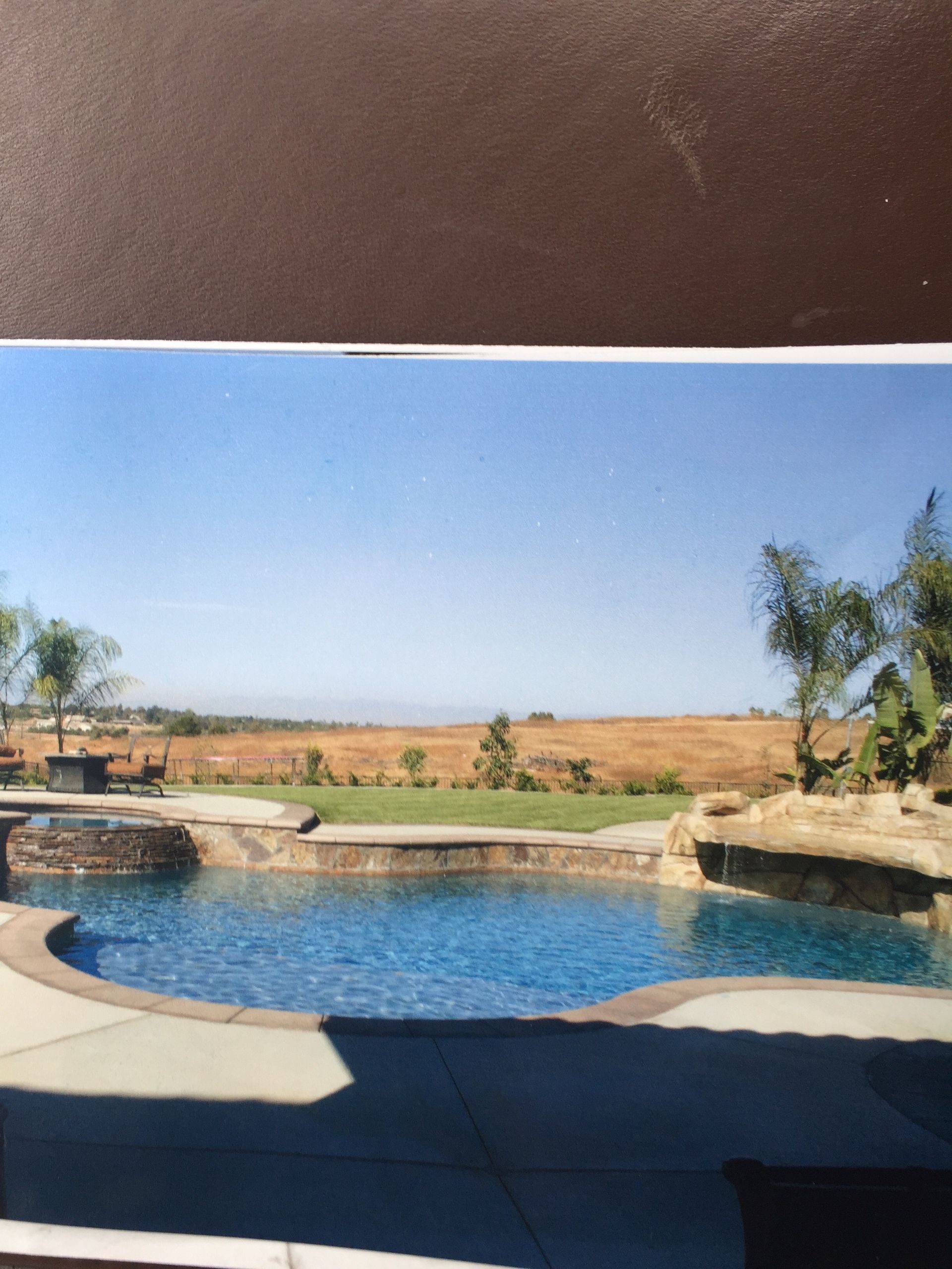 A picture of a swimming pool with a field in the background