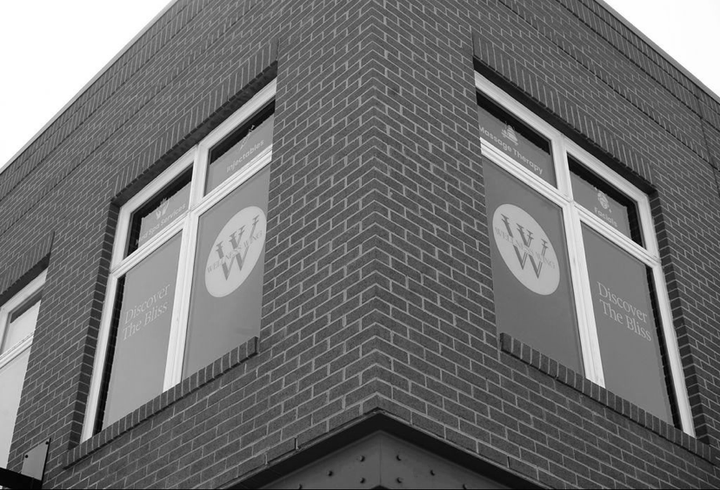 Corner of a brick building with large windows featuring a logo.