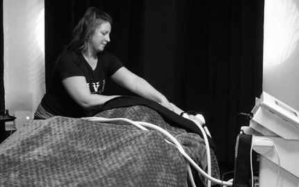 Woman working with equipment on a bed, possibly a medical procedure. Black and white.