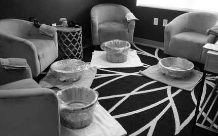 Pedicure spa with four foot basins, chairs, and patterned rug.