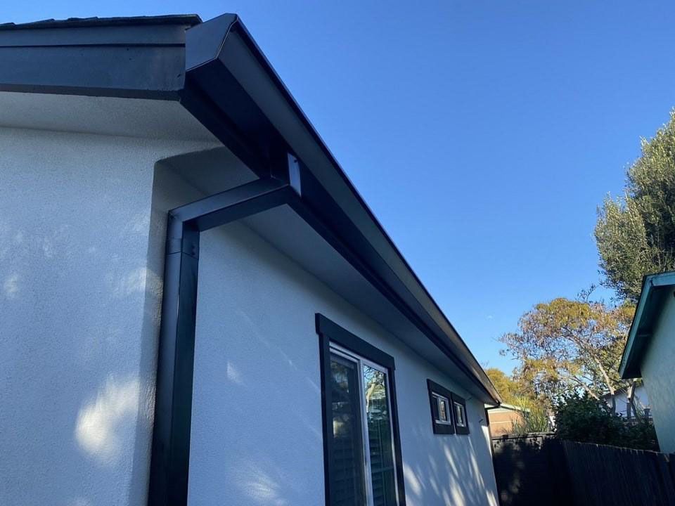White house exterior with blue trim and a sloped roof under a clear blue sky