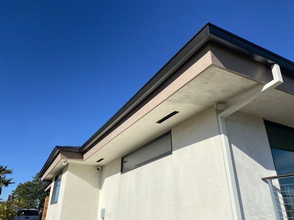 Exterior of a white house with dark roof trim under a bright blue sky