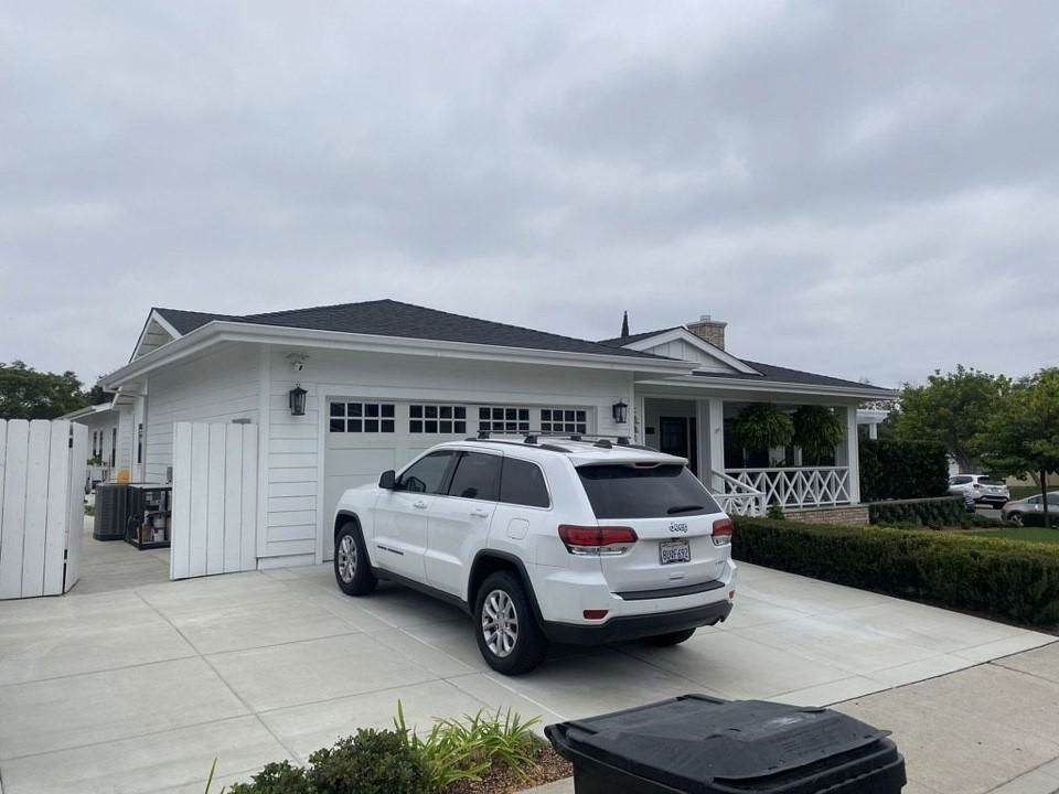 White SUV parked in a driveway beside a white garage under a cloudy sky