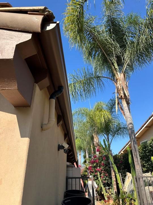 Palm trees beside a tan stucco house under a clear blue sky in a sunny courtyard
