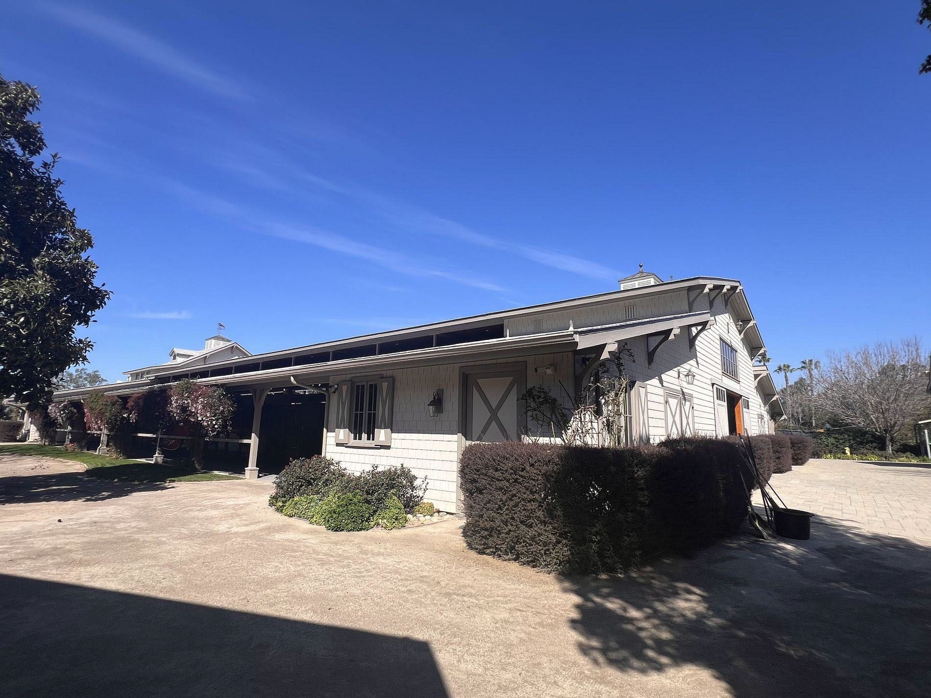 Single-story rustic house with white stucco walls and a tiled roof under a clear blue sky