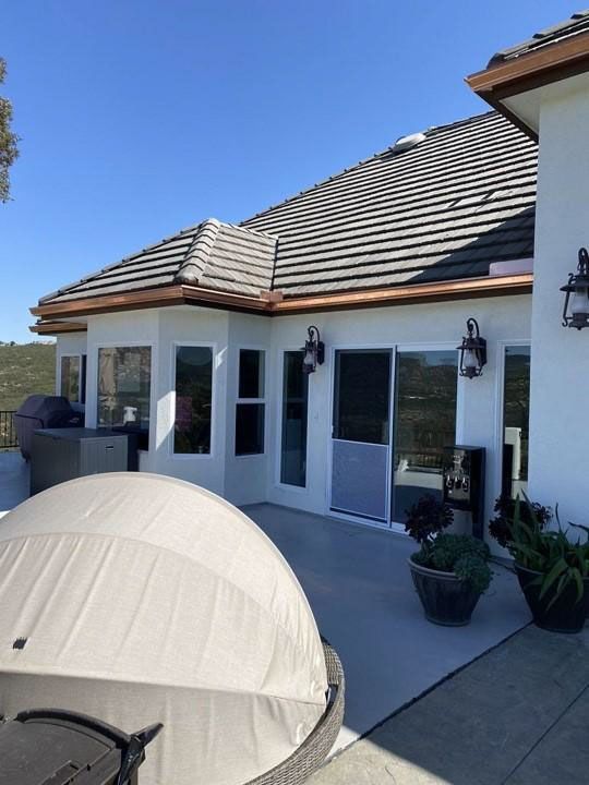 Patio with white canopy tent, potted plants, and a modern house with large windows and gray tiled roof
