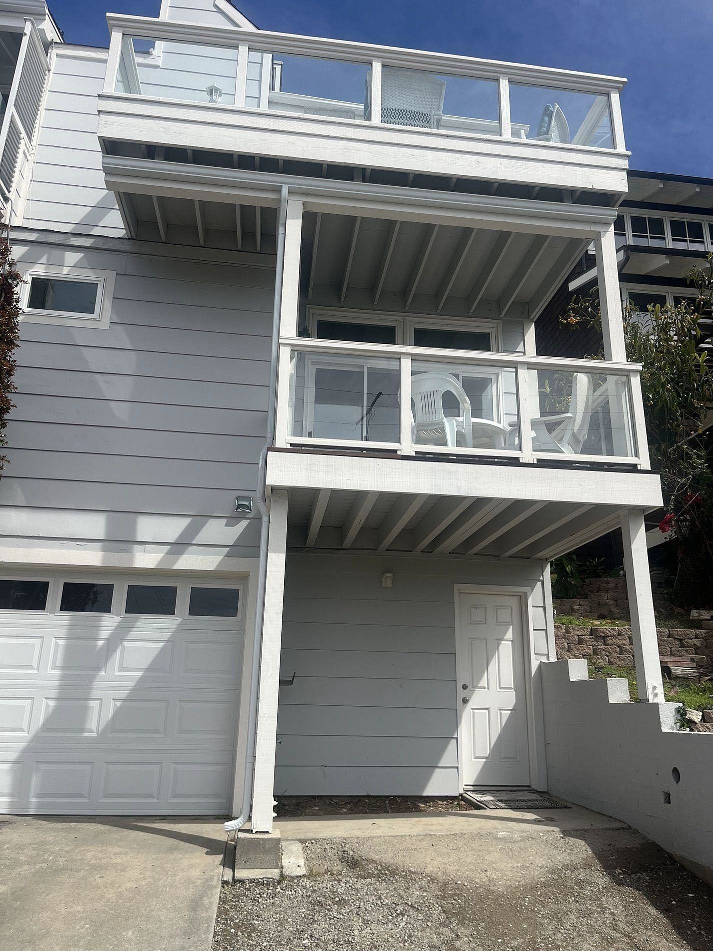 Modern gray two-story house with white trim, balcony, garage, and a small front driveway