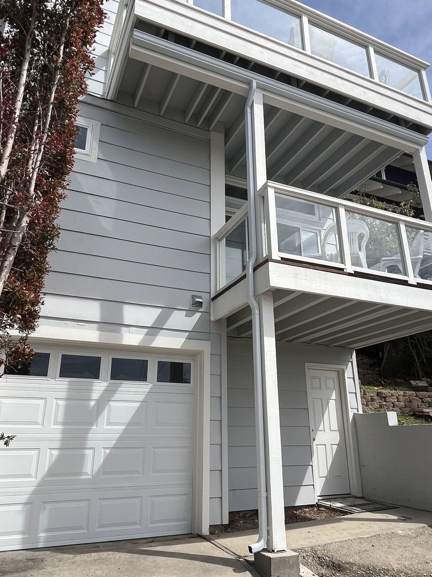 White house exterior with garage, balcony, and support columns under a covered deck
