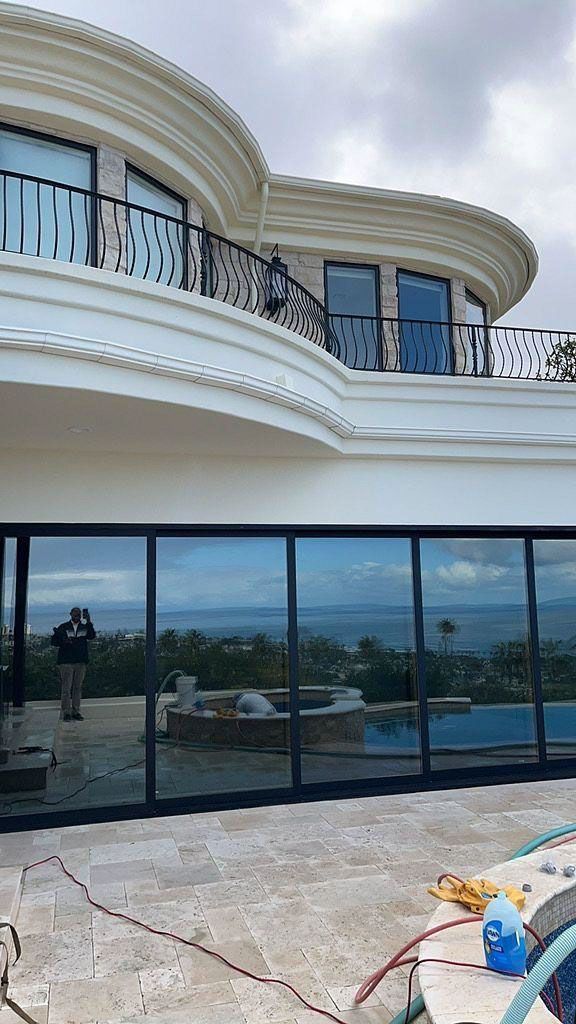 Modern white villa with curved balconies and glass walls overlooking a pool and ocean view