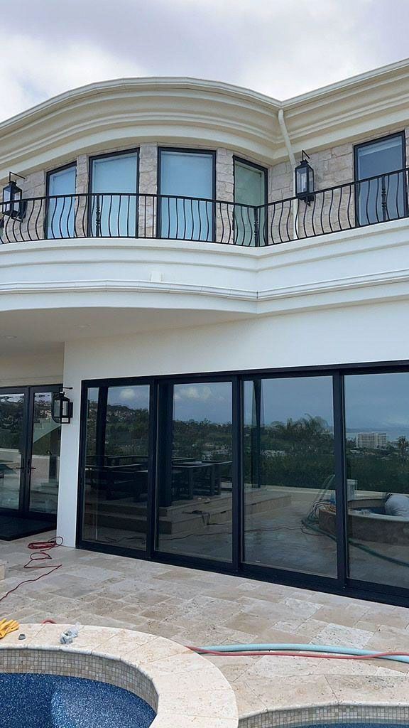 Modern white two-story house with curved balconies and large black-framed glass doors overlooking a pool