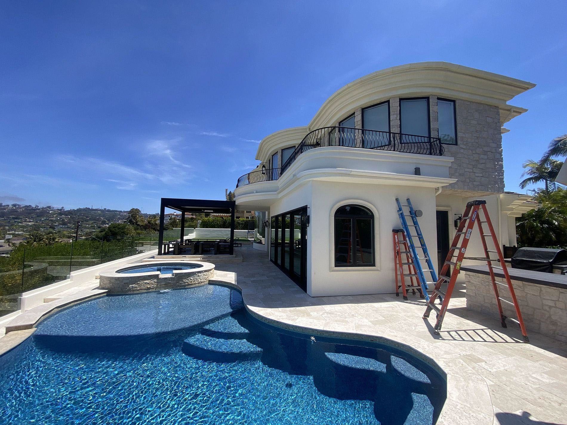 Luxury villa with blue-tiled pool and red ladders on a sunny hillside patio
