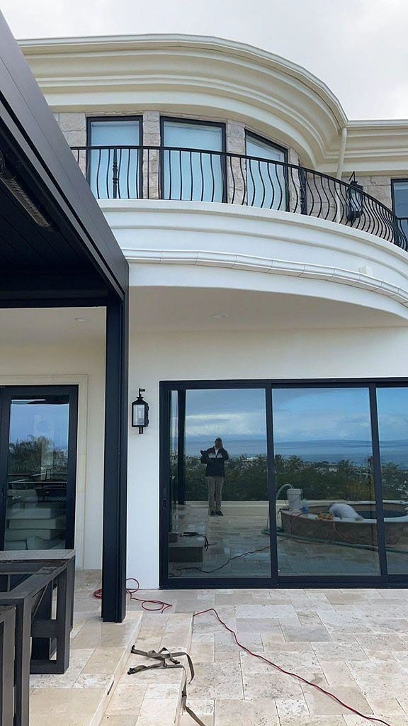 Modern house patio with curved balcony, black-framed sliding doors, and distant landscape reflections