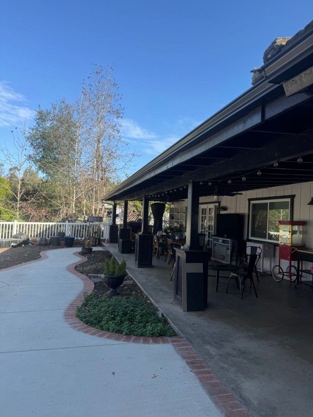 Outdoor patio with tables, chairs, and potted plants beside a building under a clear blue sky